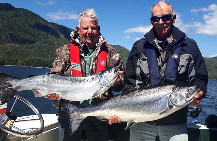 Two anglers on a BC fishing charter holding large salmon fish, showcasing their catch during a fishing trip.