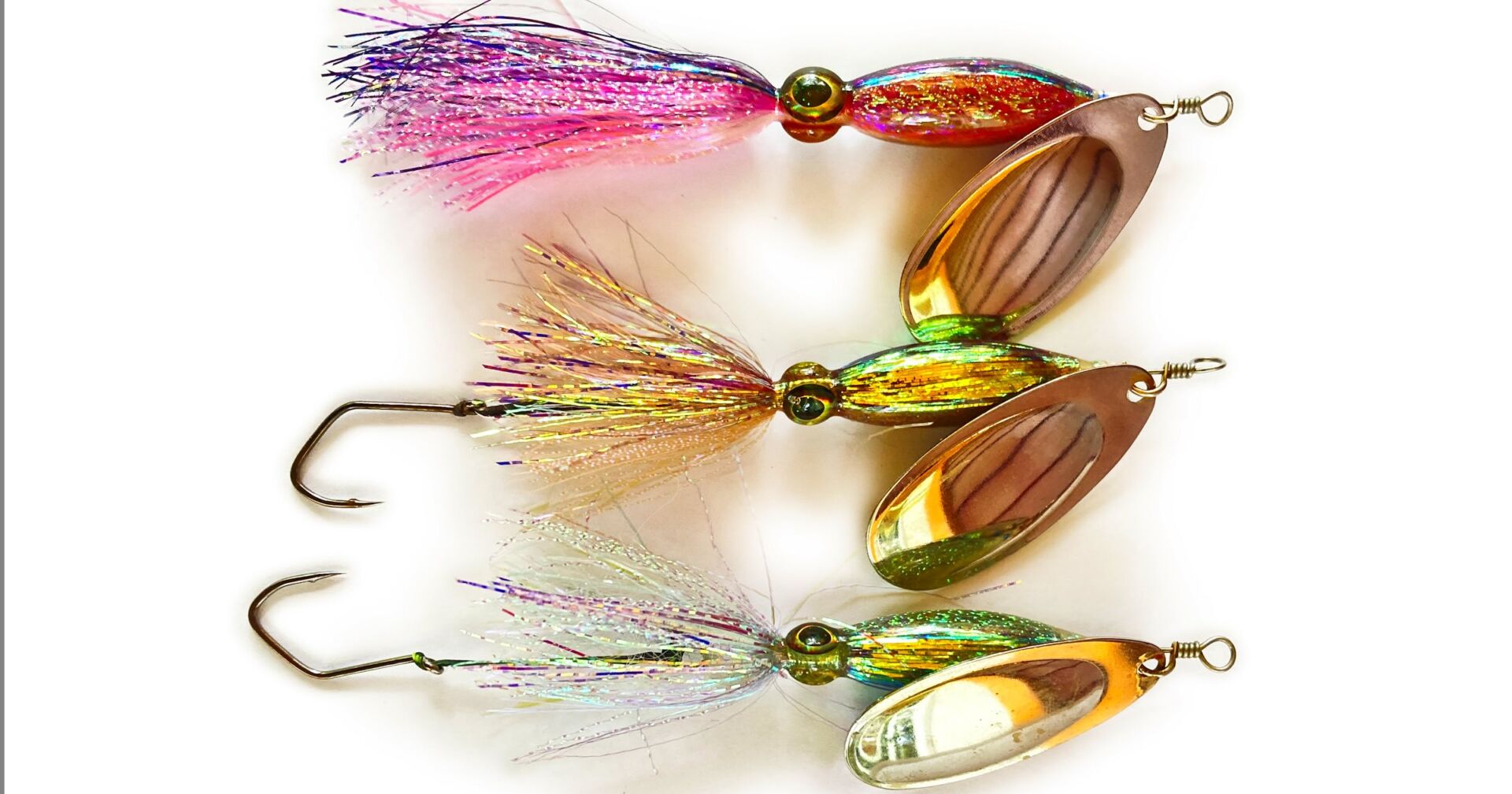 Three squid spinners with colorful tinsel skirts and reflective blades, designed for beach salmon fishing.