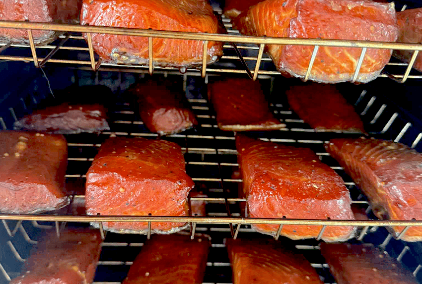 Hot-smoked salmon fillets on wire racks inside a Bradley Smoker showing a rich mahogany colour and glossy finish.