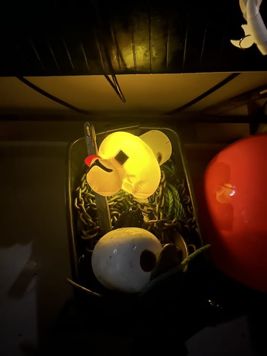 Duck Hunting: The Wild World of Float Fishing for Halibut The modified solar pool chlorinator duck float glowing bright yellow in the dark inside a boat's anchor chain box.