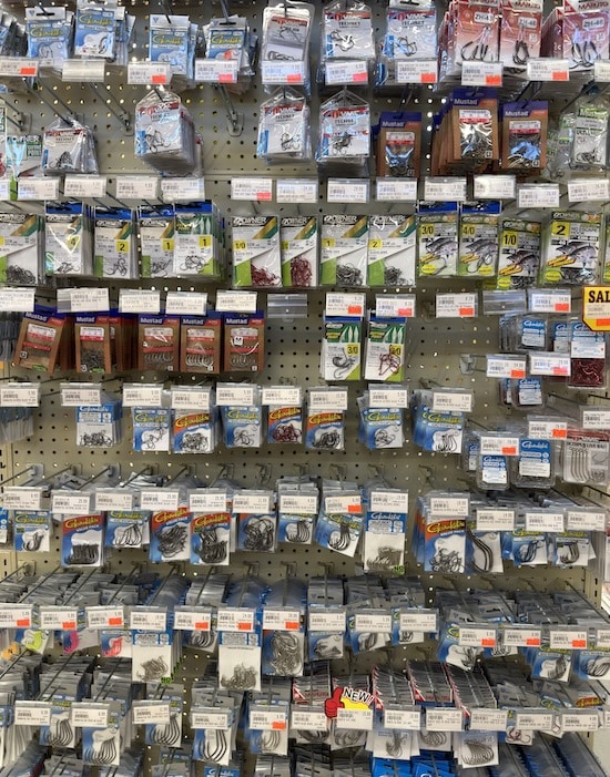 A massive retail pegboard wall of salmon fishing hooks and single barbless terminal gear affected by the DFO Regulations 2026.