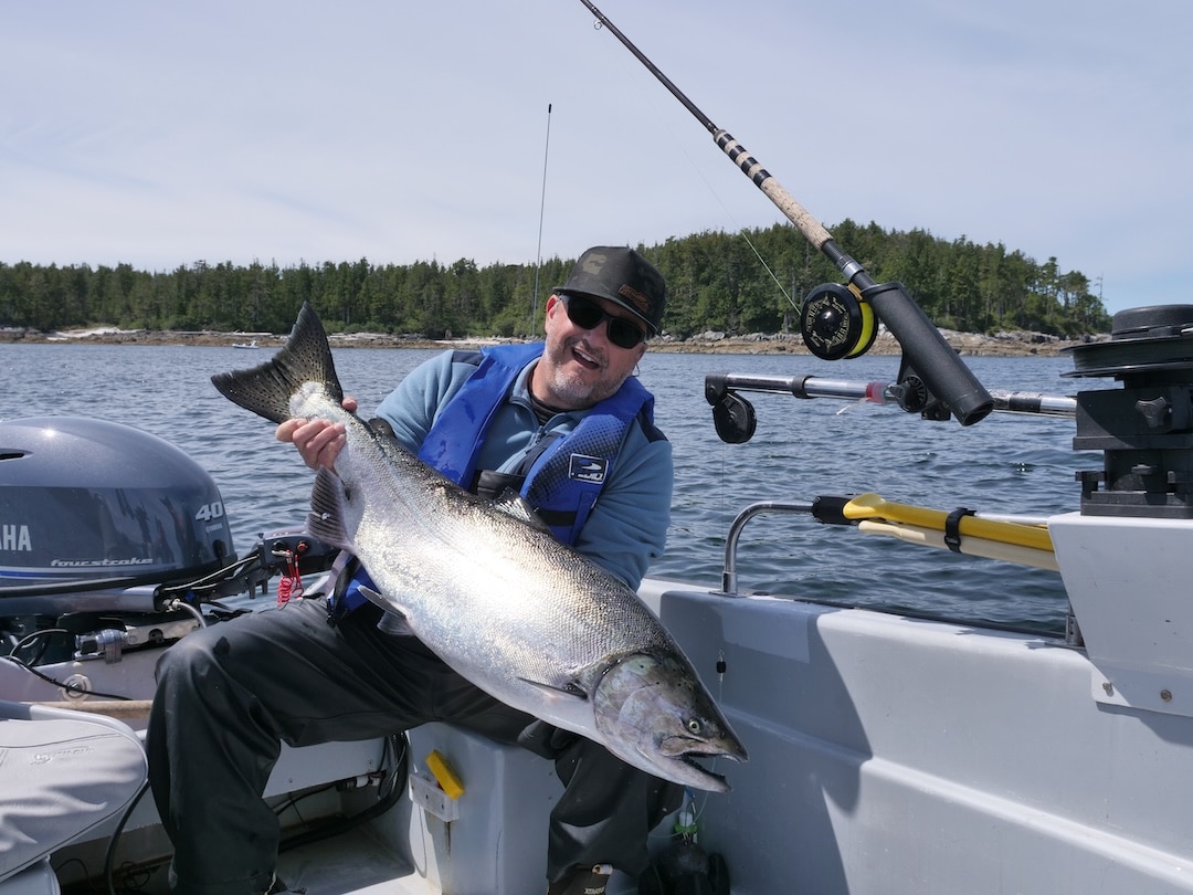 Understanding the Proposed BC Sport Fishing Regulation Updates Angler holding a Chinook salmon while reviewing BC sport fishing regulation updates.