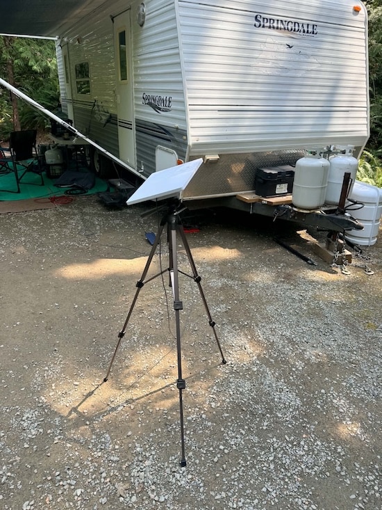 A Starlink Mini for boat and truck travel set up on a camera tripod outside a Springdale camper trailer while dry camping on Vancouver Island.