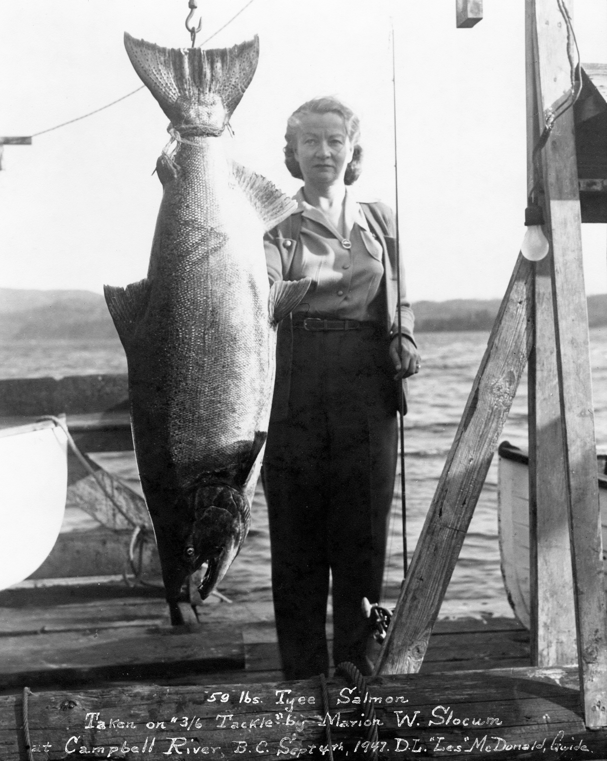 Marion W Slocum standing beside her 59 lb Tyee salmon caught on 3/6 tackle at Campbell River in 1947