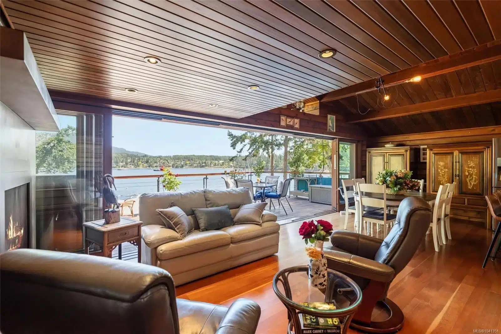 Coastal Luxury: 10968 Madrona Drive in Deep Cove Open-concept timber-frame living room with folding glass wall opening to ocean views.